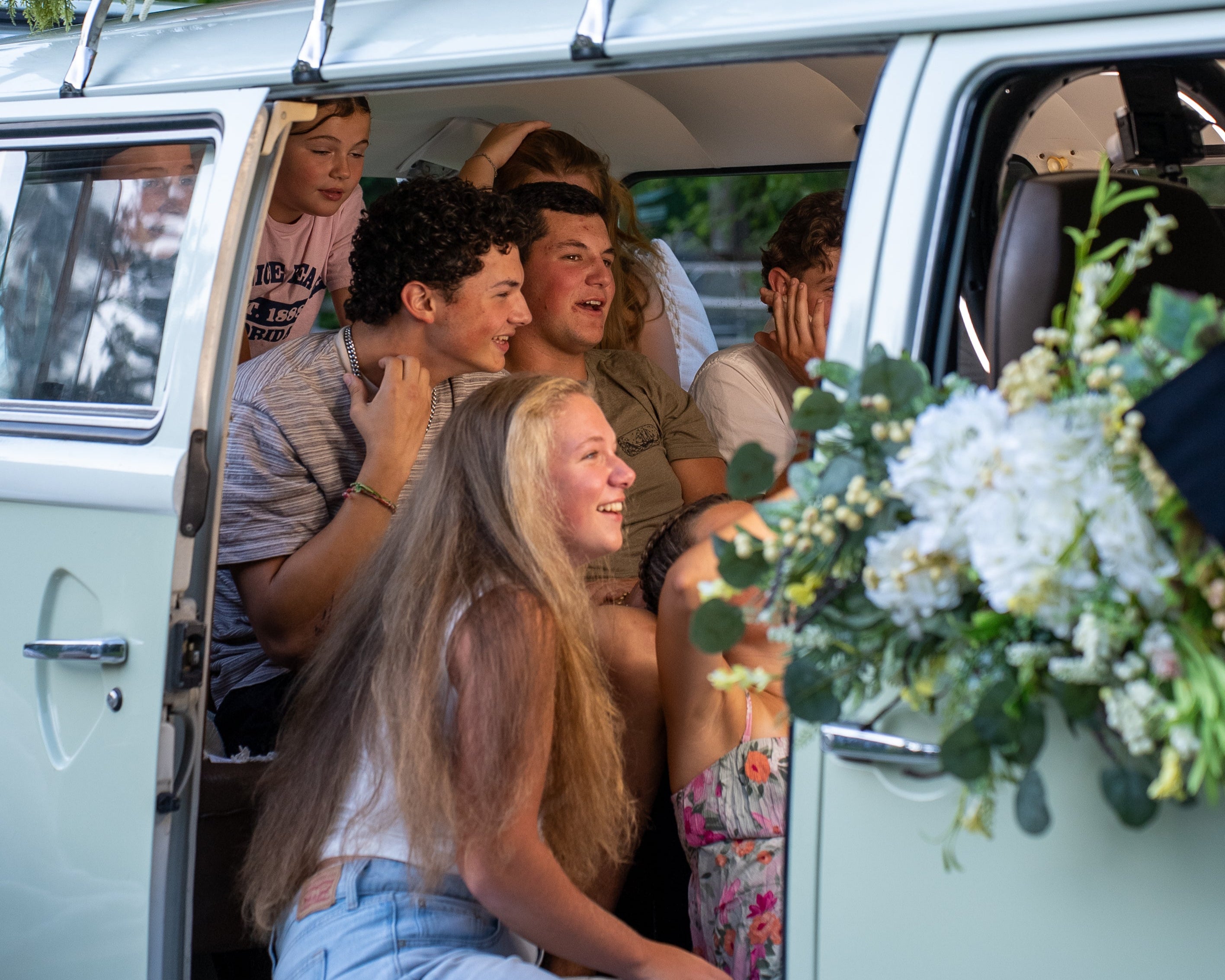 a group of teenages in a green vw bus that is a photo booth smiling at the camera